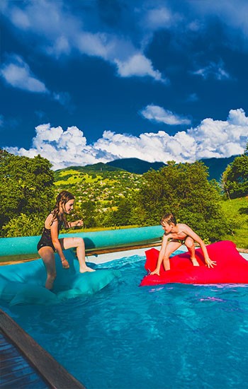 Pouf Piscine Enfant, enfants sur un pouf flottant coloré dans l’eau de la piscine
