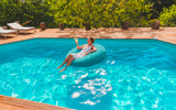 Pouf Rond Piscine Turquoise flottant sur l’eau de la piscine, moment détente en extérieur