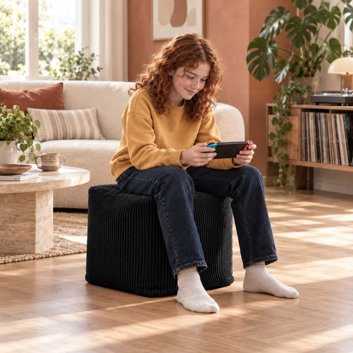 Pouf Cube Velours Côtelé Noir — pouf carré en velours côtelé noir, assise d’appoint ou repose-pieds, dans un salon lumineux