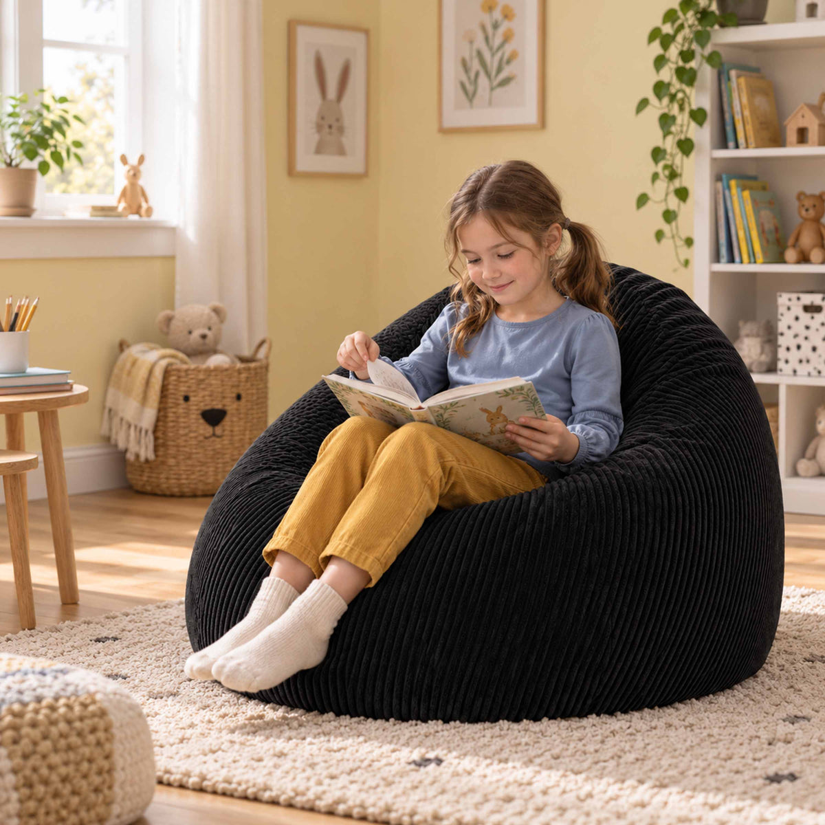 Pouf Poire Velours Côtelé Noir : enfant lisant sur un pouf poire noir en velours côtelé, salon cosy