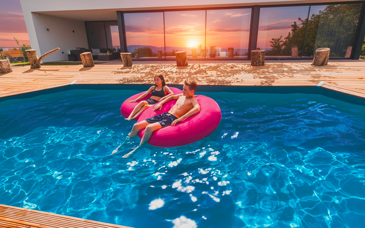 Pouf Rond Piscine Rose : deux enfants se détendent sur un matelas flottant rose dans une piscine extérieure